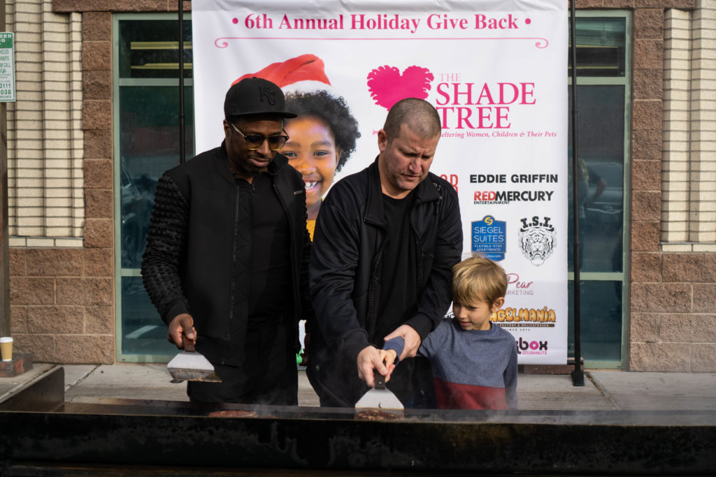 Eddie Griffin, Darin Feinstein, and child flip burgers for The Shade Tree charity event.