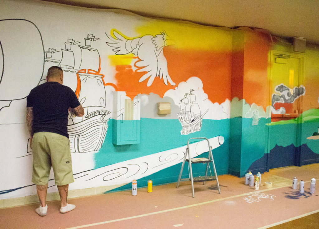 ISI Group artist works on indoor mural for The Shade Tree.