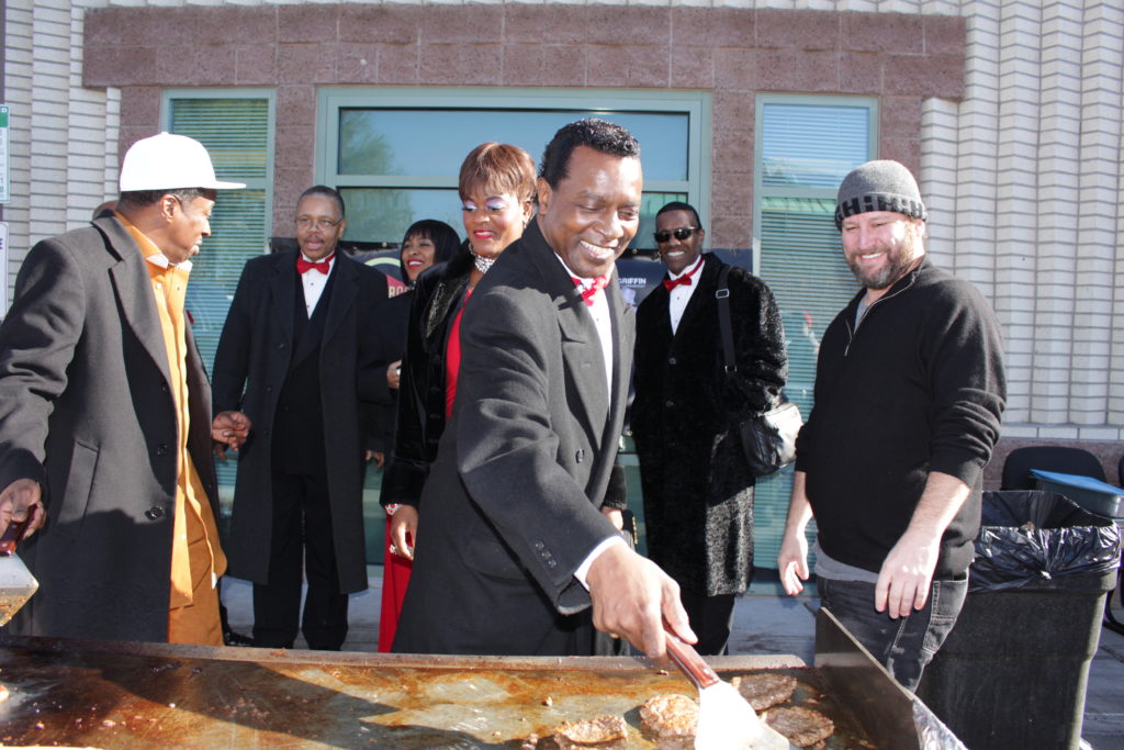 Darin Feinstein, Eddie Griffin, and Shade Tree supporters flip burgers for holiday event.