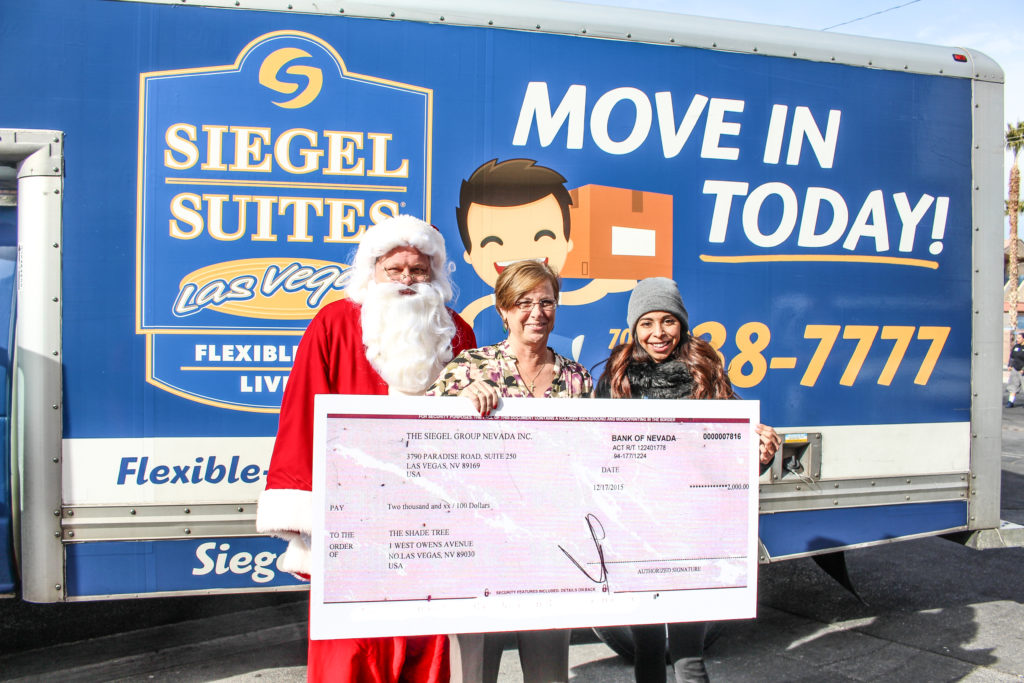 Santa Claus, Marlene Richter, Judi Siegel pose with a check for The Shade Tree.